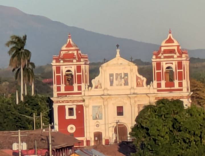 Zoomed image of a red and white colonial church with distant mountain backdrop.