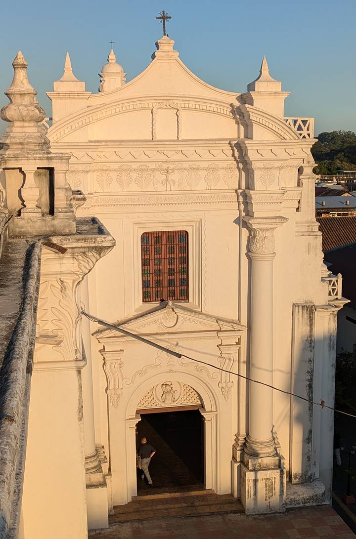 Architectural detail of León Cathedral rooftop showing ornate window and columns in warm evening sun.