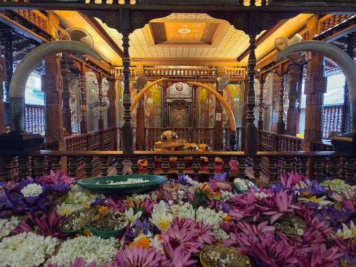 Richly decorated interior of a Buddhist temple with carved columns and vibrant lotus offerings.