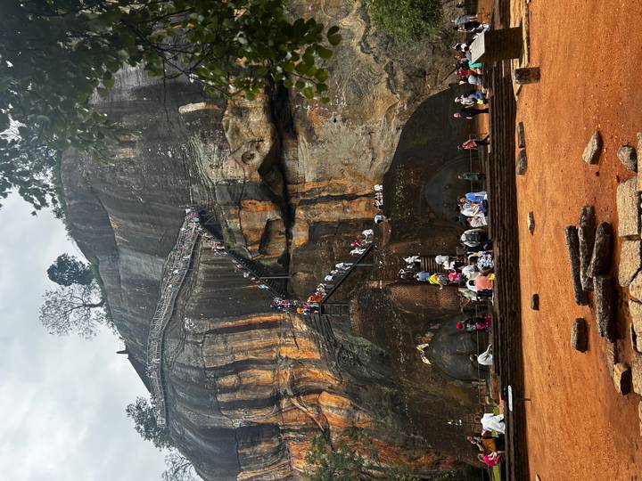 Long lines of visitors climb the dramatic stairway cut into Sigiriya's orange rock face.