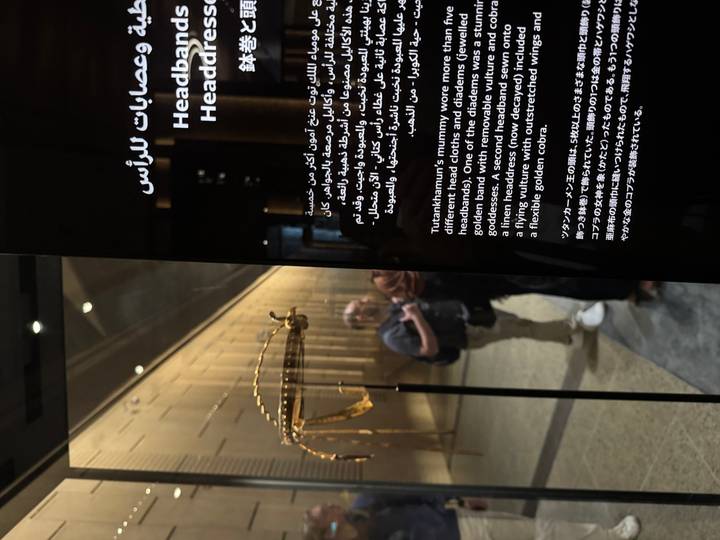 Museum display panel with English and Arabic text partly obscures visitors in background.