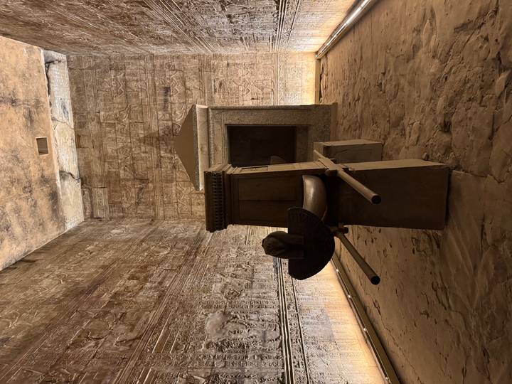 Inner sanctuary of ancient temple with stone ceremonial barque and richly carved walls.