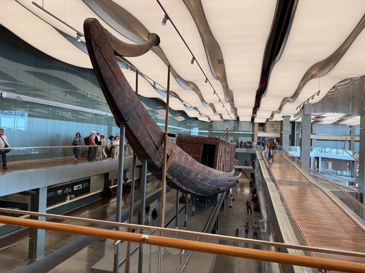 Grand Egyptian Museum hall featuring full-scale ancient wooden solar boat suspended above walkways.