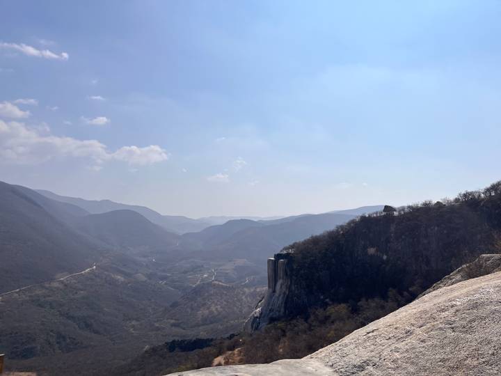 Mountain landscape of Hierve el Agua with mineral cliffs and layered valleys under hazy sky.