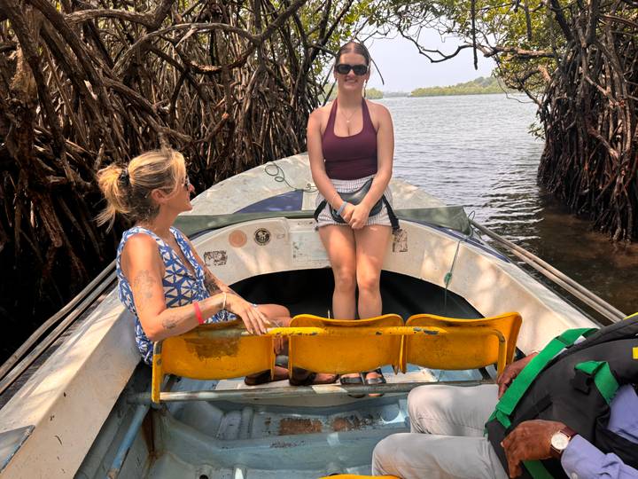 Two young women enjoy a small motorboat ride through mangrove-lined waterways.