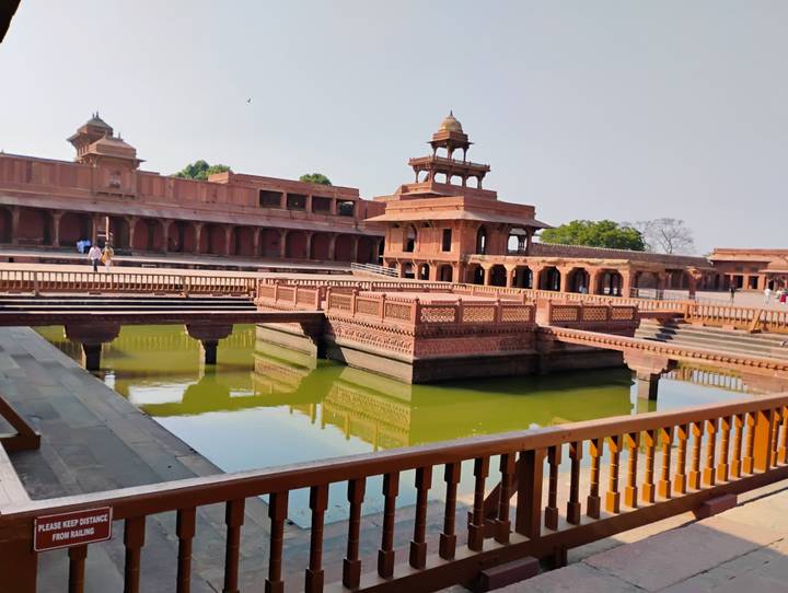 Panch Mahal and reflecting pool at Fatehpur Sikri palace complex in soft sunlight.