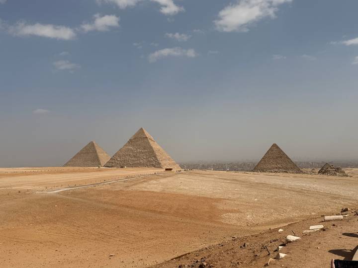 Iconic trio of Giza pyramids rising from the desert plain under hazy skies.