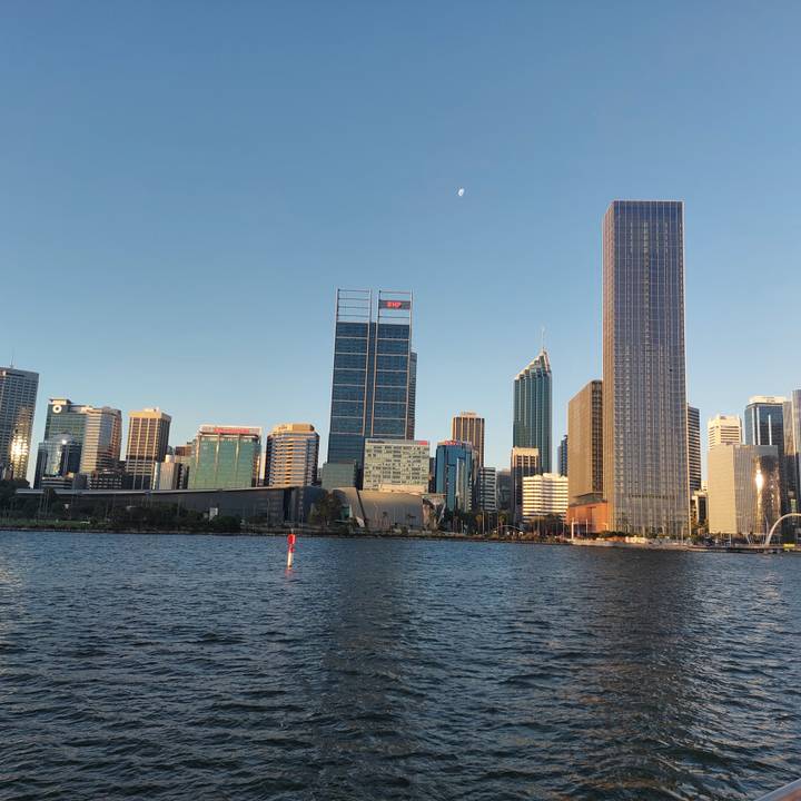 Perth’s evening skyline reflects warm sunset tones above gentle river waters.