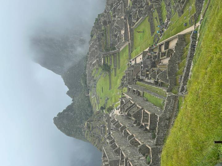 Machu Picchu’s stone terraces and temples emerge from lush green slopes under drifting mist and towering peaks.