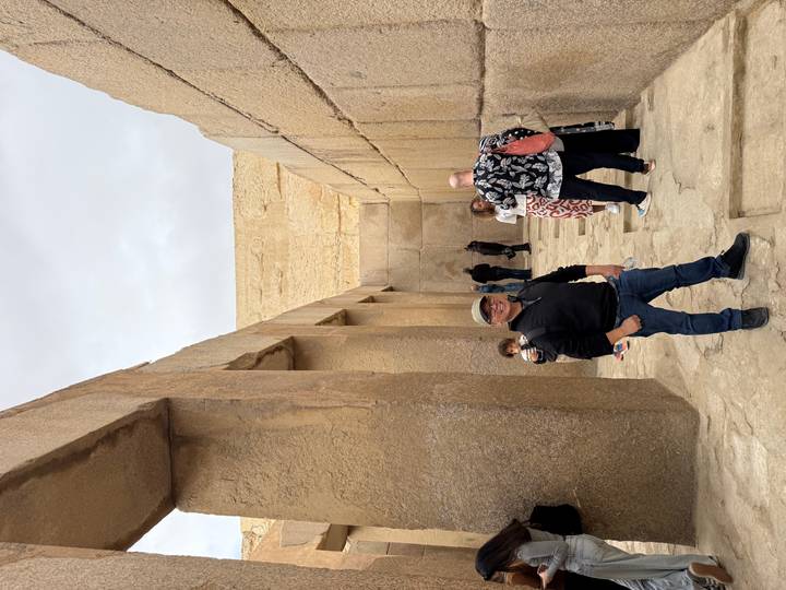 Tourists explore a narrow ancient stone corridor near the pyramids.