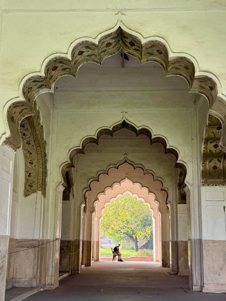 Series of scalloped Mughal arches with intricate floral details inside an Indian palace