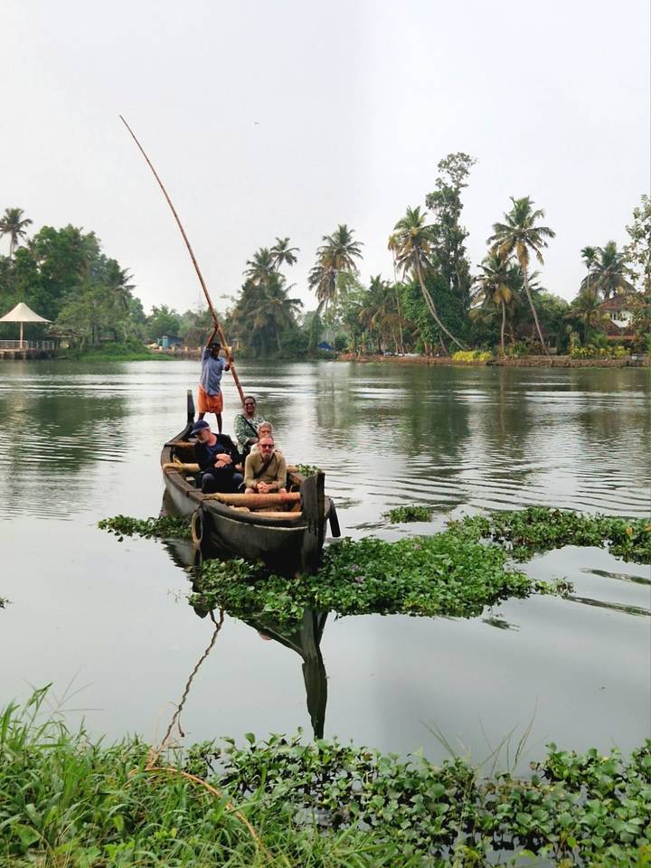 Small wooden canoe with tourists paddling through calm tropical backwaters