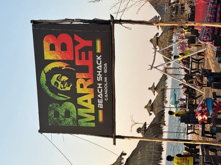 Bob Marley Beach Shack sign on Candolim beach with thatched umbrellas and visitors