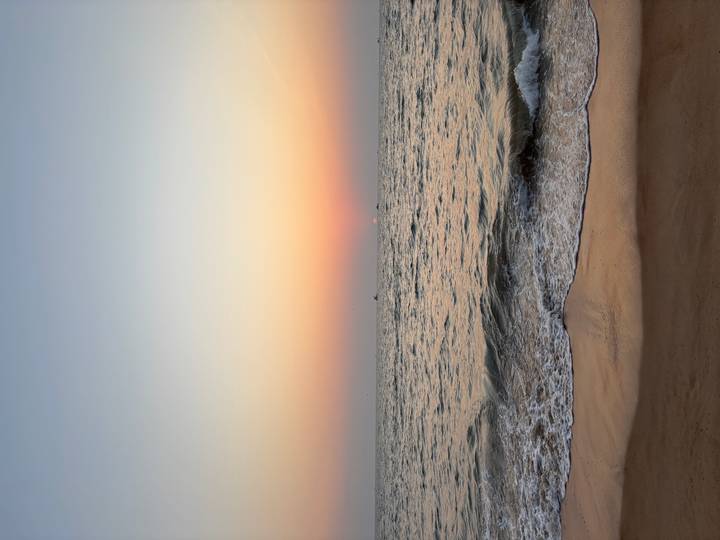 Serene sunset over Arabian Sea with gentle waves lapping sandy shore