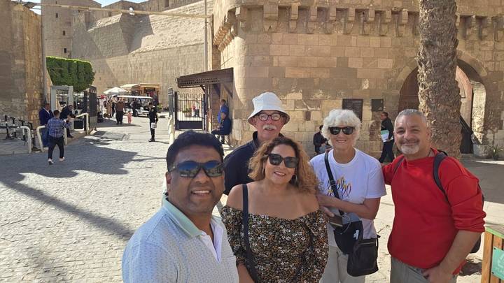 Small group smiling in the sunlit courtyard outside Cairo’s medieval citadel walls.