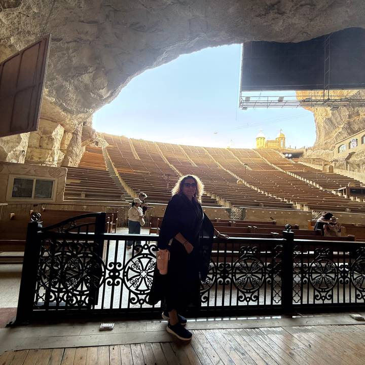 Visitor standing inside Cairo’s cavernous Cave Church amphitheatre with rows of wooden benches.