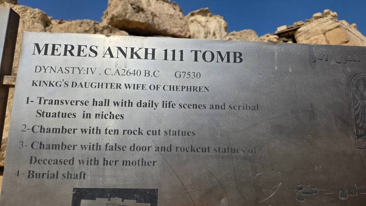 Metal information plaque describing the Meres Ankh III tomb with ruins blurred behind