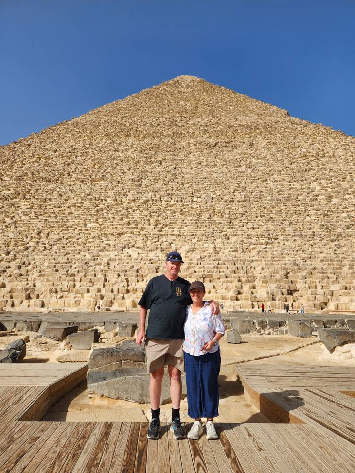Travellers posing against the immense stepped stones of the Great Pyramid of Giza