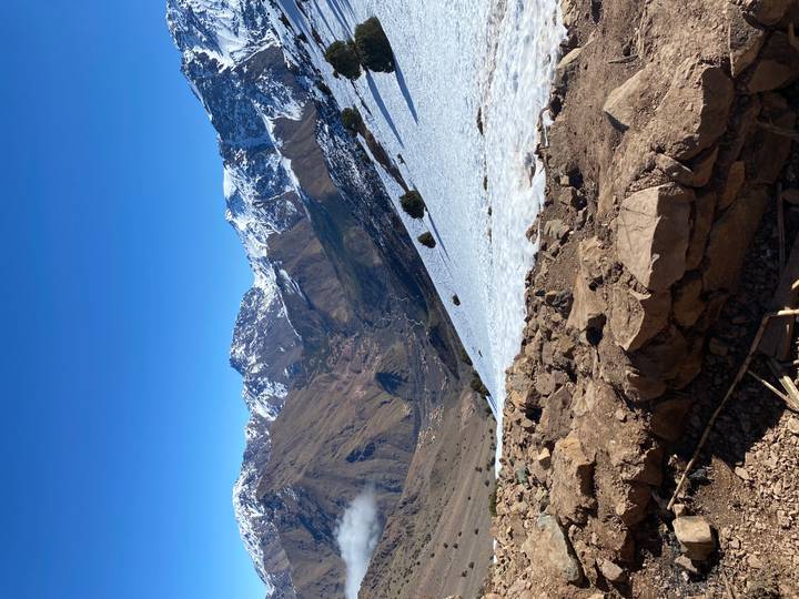 Snow-capped Atlas mountain range under a clear blue sky with a valley far below.