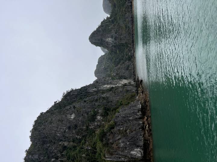 Emerald green water surrounded by dramatic limestone karst cliffs and rocky shoreline