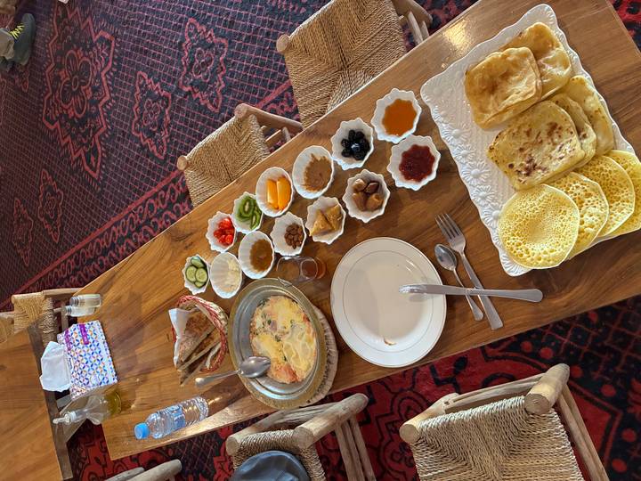 Traditional Moroccan breakfast spread with breads, jams and eggs on wooden table.