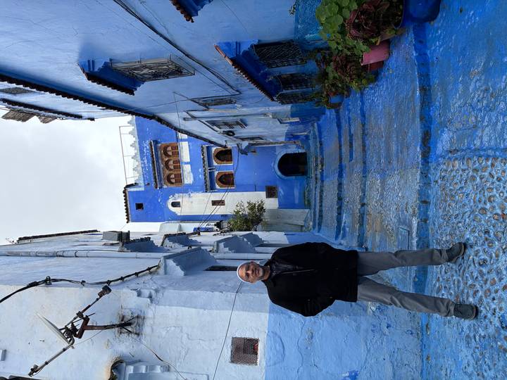 Man standing in the famous blue-painted alleyways of Chefchaouen.
