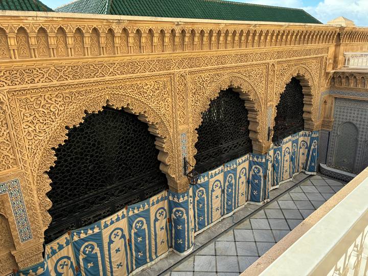 Intricately carved arches and tiled walls inside a Moroccan palace courtyard.