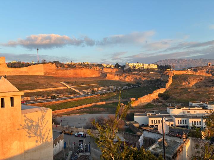 Sunset view across ancient fortified walls and hills surrounding a Moroccan city with warm golden light
