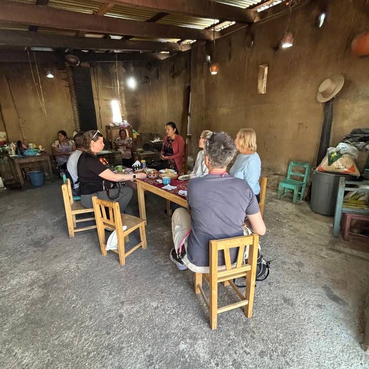 Travellers share a meal inside a rustic adobe home during a cultural visit.