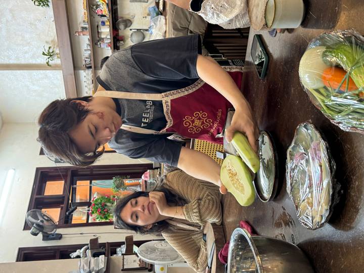 Cooking instructor slicing a pale green gourd while a student observes during class.