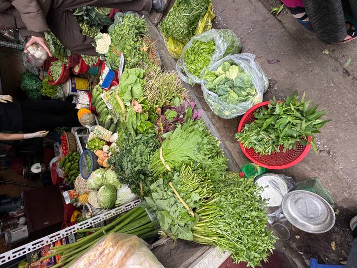 Colorful assortment of fresh leafy vegetables and herbs displayed in baskets at a market stall.