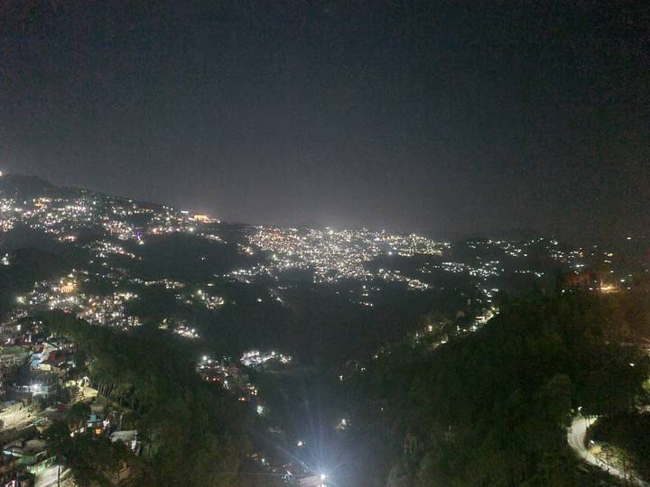Nighttime panoramic view of a hillside town sparkling with countless lights.