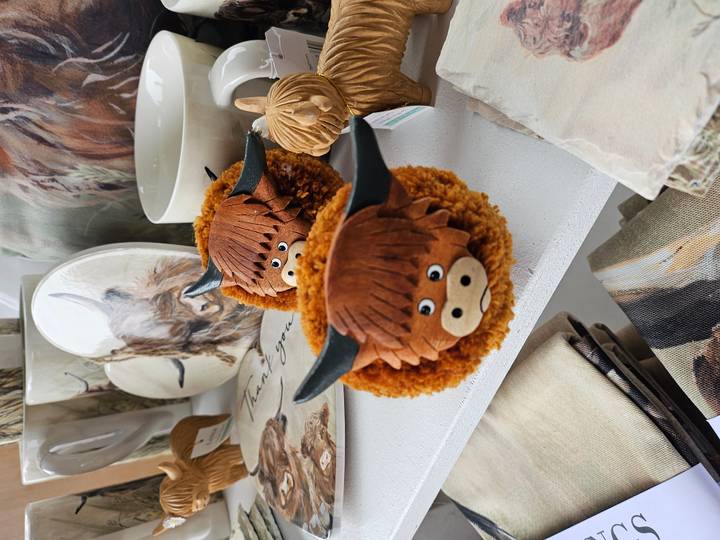Cute Highland-cow themed souvenirs displayed on a white shop shelf