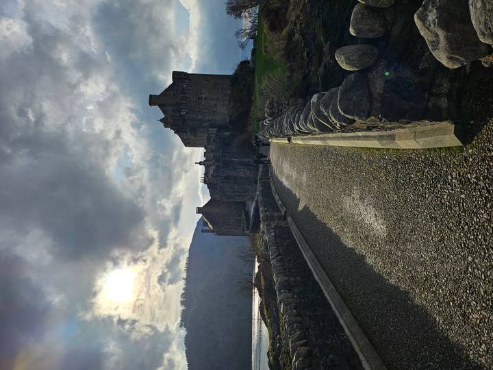 Moody view of Eilean Donan Castle at the end of a stone bridge under dramatic sky