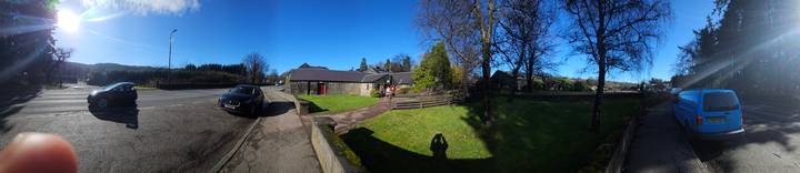 Bright village scene with stone buildings, green lawn and photographer shadow in foreground