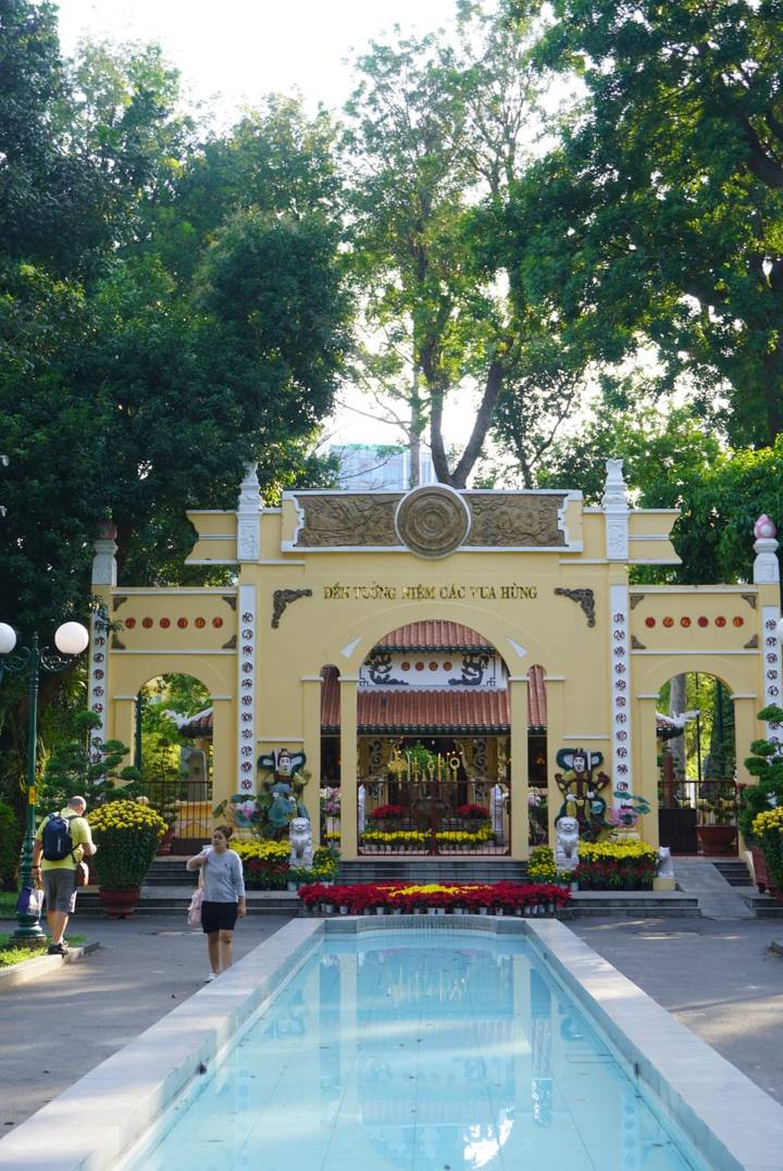 Decorative yellow gateway in a leafy park with a handful of sightseers.