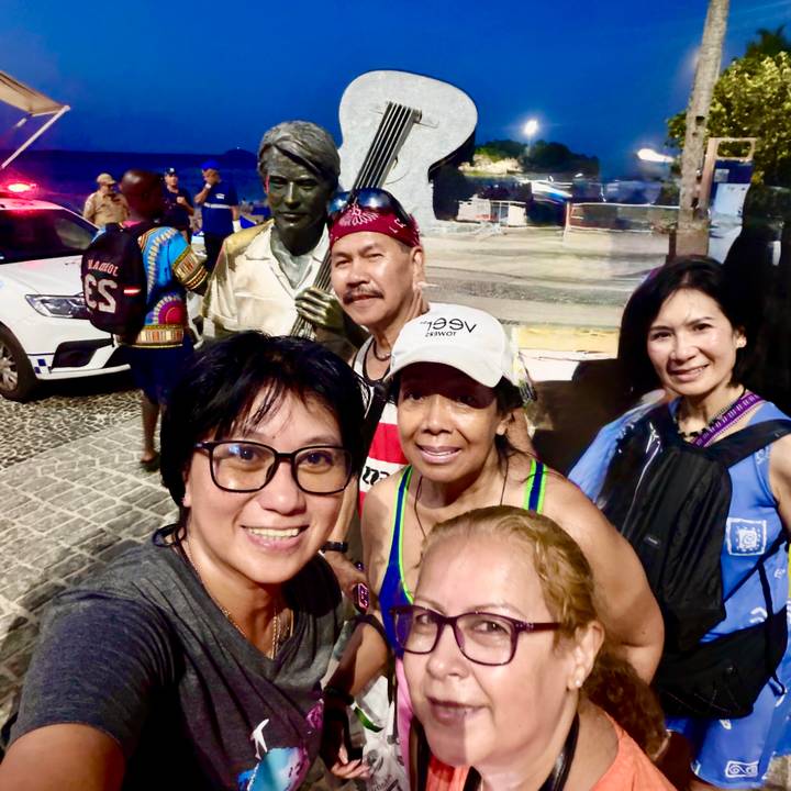 Group selfie with bronze street statue at night during city outing.