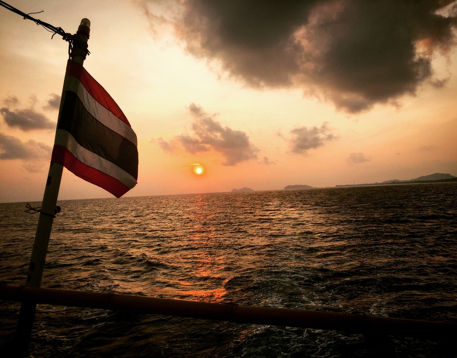 Sunset over the ocean with a Thai flag in the foreground.
