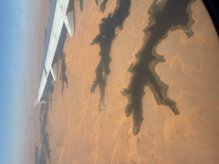 Aerial view from airplane window over vast Saharan desert with branching dark wadis