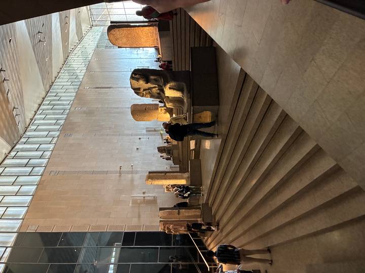 Grand hall of new Egyptian Museum with monumental statues and visitors exploring the exhibits