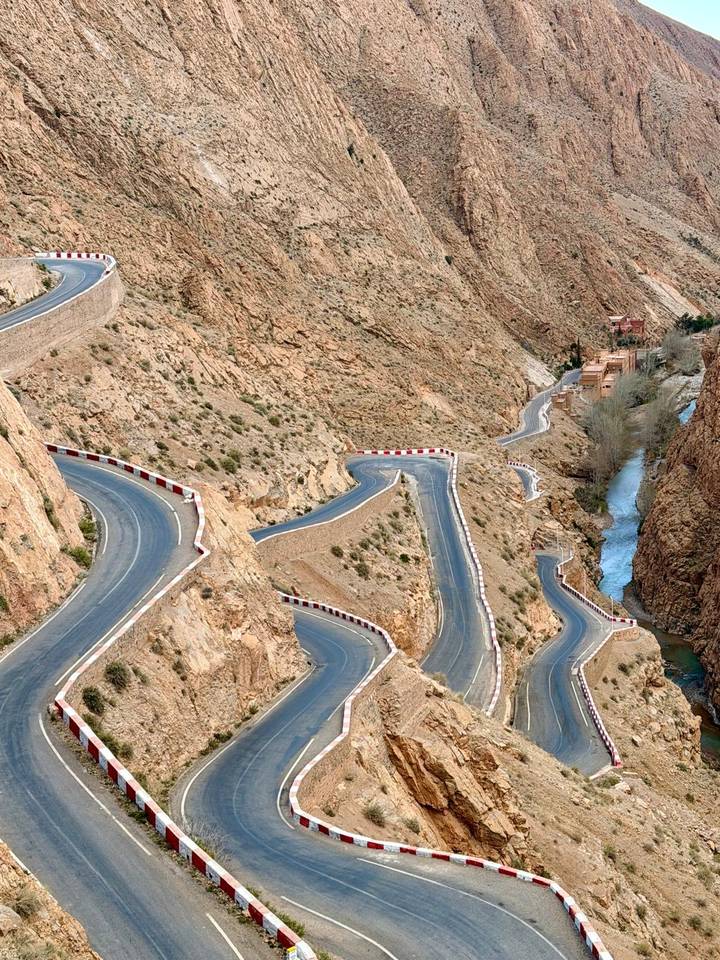 Dramatic serpentine mountain road winding through gorge with river at its base in Morocco