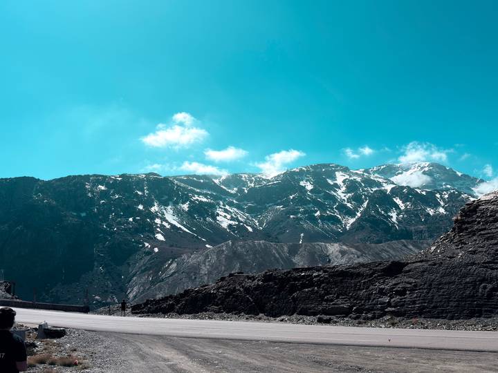 Snow-streaked peaks of the High Atlas Mountains under a brilliant turquoise sky.