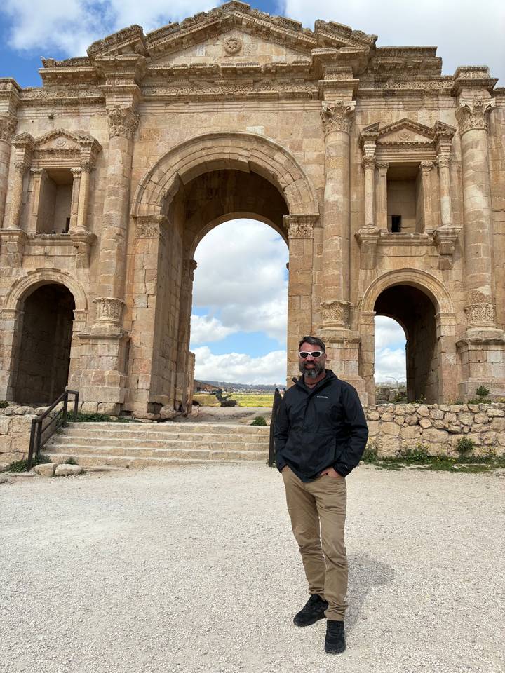 Man standing before the grand Hadrian’s Arch at Jerash archaeological site
