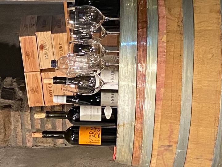 Selection of wine bottles, glasses and wooden cases arranged on a barrel in a cellar