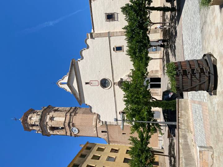 Historic church with clock tower opening onto a sunny town square