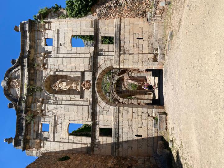 Stone gateway ruins with a cyclist visible through the central arch