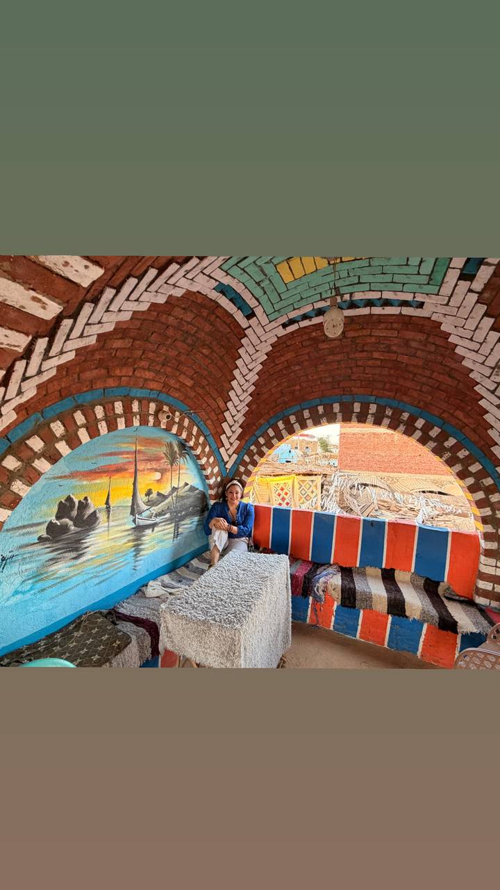 Traveler relaxing inside a brightly painted Nubian house with artistic murals.