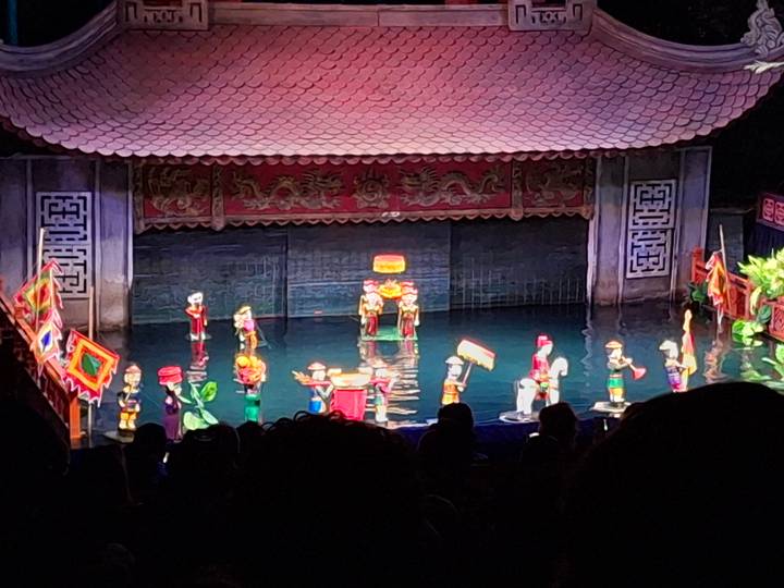 Colorful Vietnamese water-puppet show with small figures performing on a water stage.