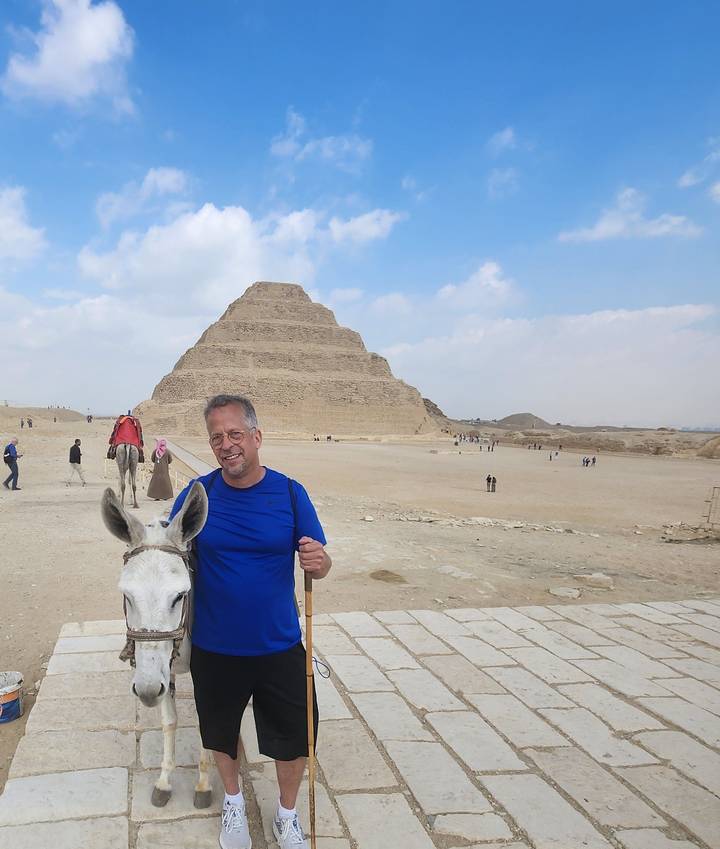 Traveller with a donkey poses in front of the Step Pyramid of Djoser in the Saqqara desert.