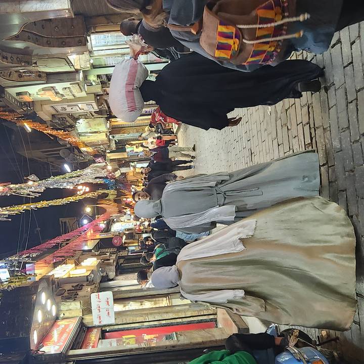 Bustling evening market street lined with colourful hanging textiles and crowds in Cairo.